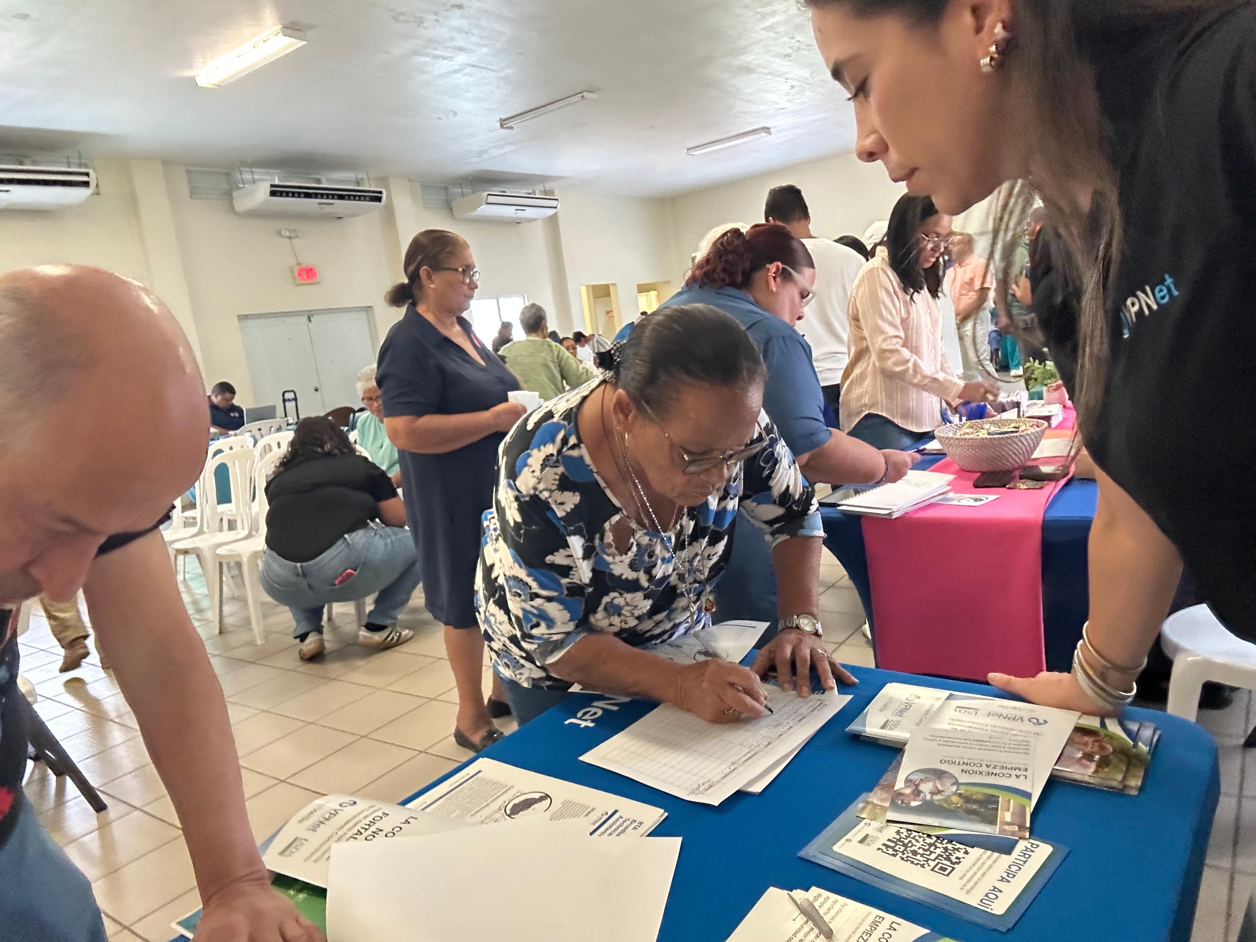 Residente llenando el registro en la mesa de vpnet durante un evento comunitario